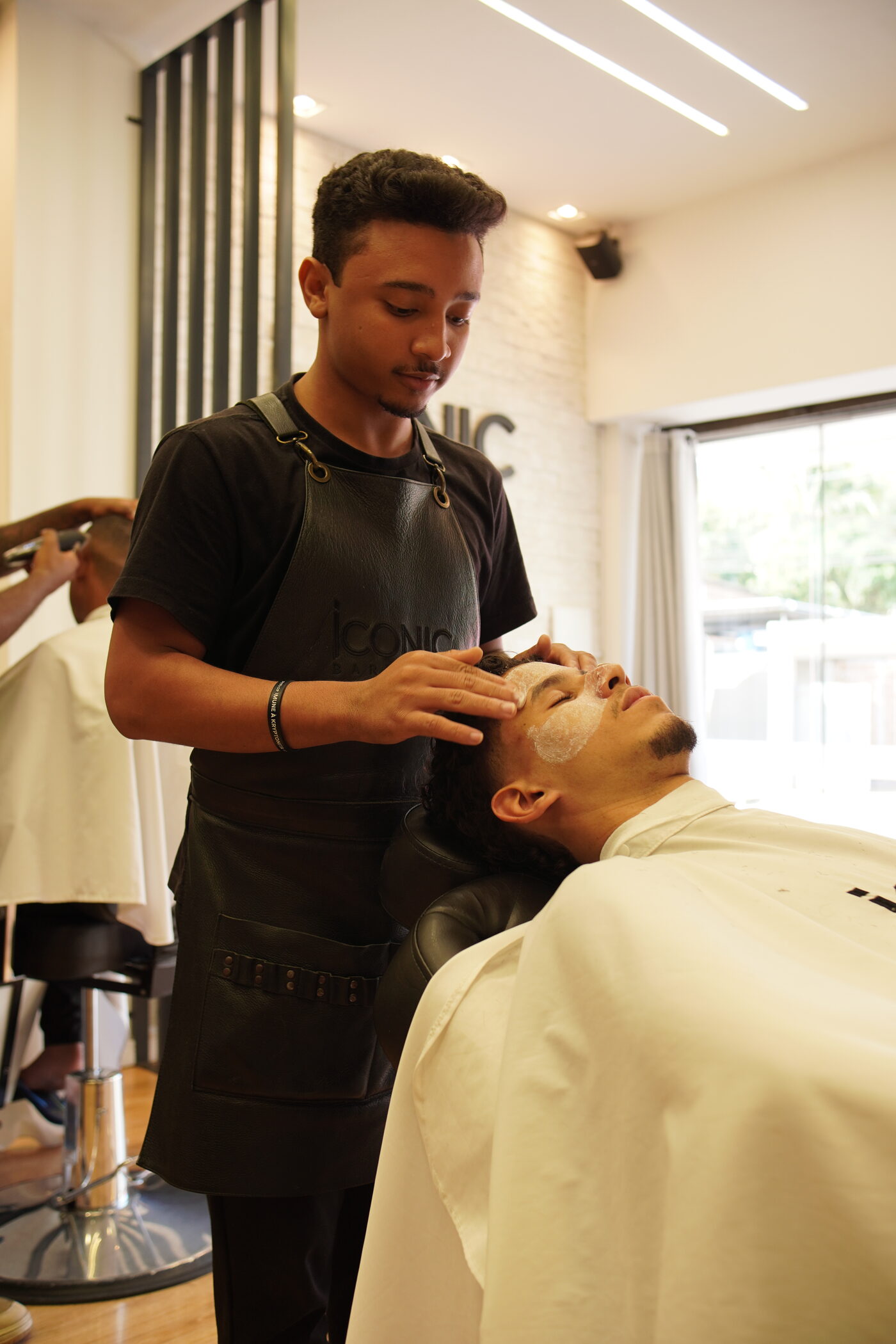 Barbeiro aplicando finalização facial em cliente