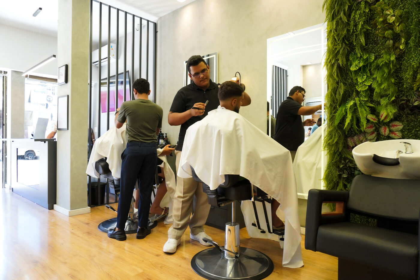 Movimento de clientes e barbeiros na Iconic Barbearia